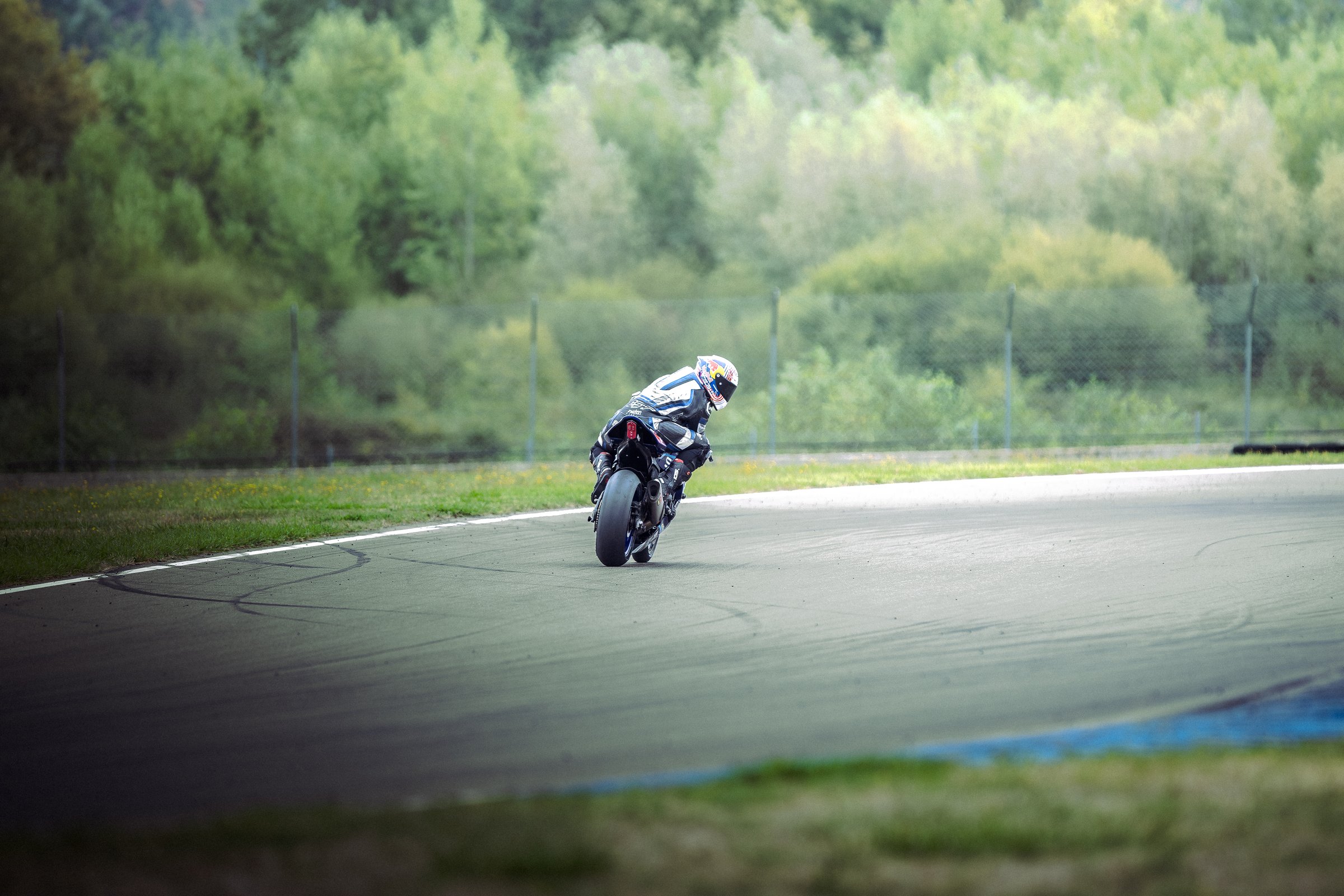 Photographe pilote moto - wheelie en sortie de virage sur circuit verdoyant